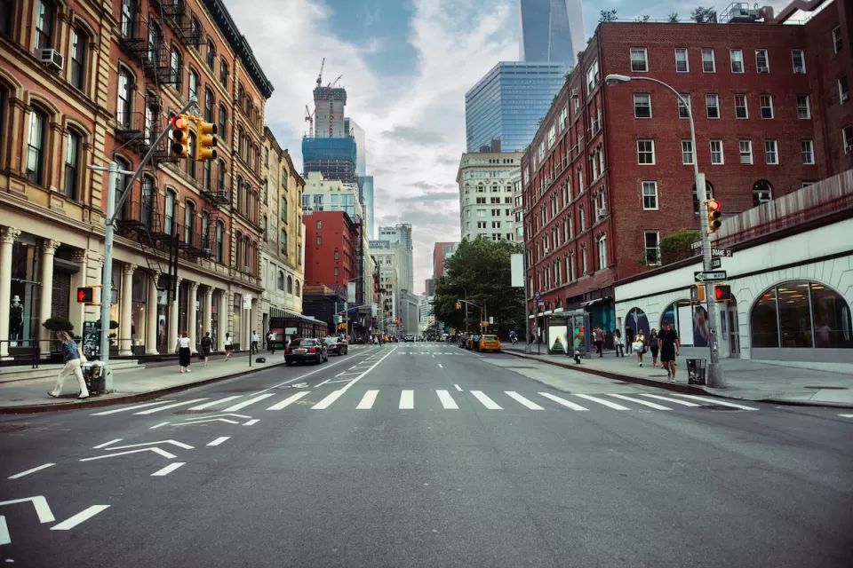 New York City street with painted bike lane and crosswalk flanked by brick buildings.